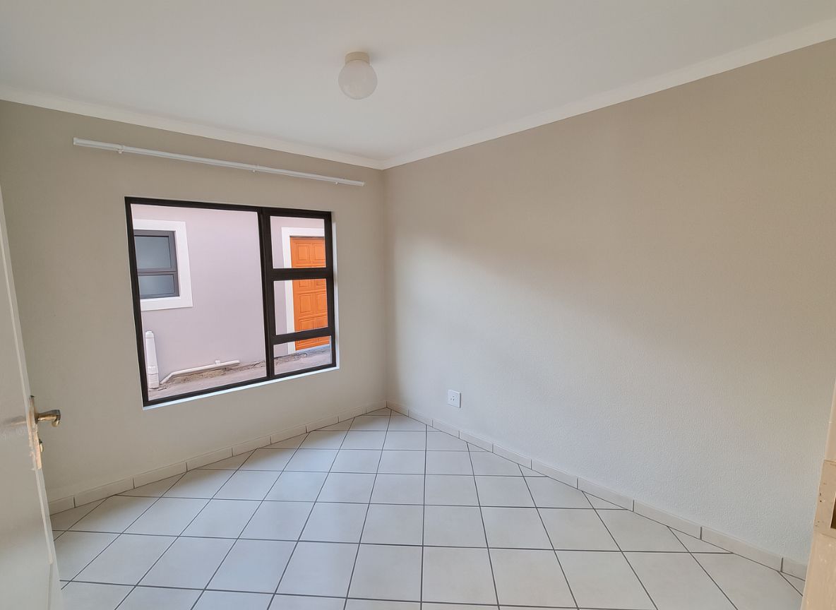 Modern bedroom with grey tiled floors leading into an ensuite bathroom in the Crystal Park development.
