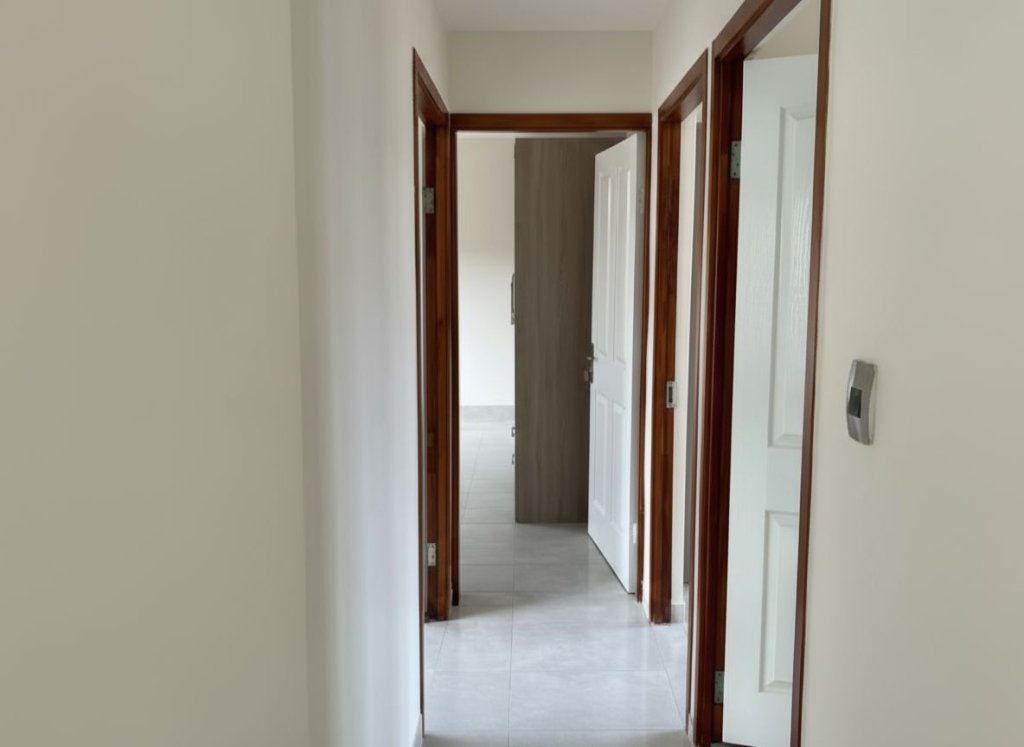Bright tiled hallway in a Crystal Park home showing access to multiple bedrooms with wooden door frames.