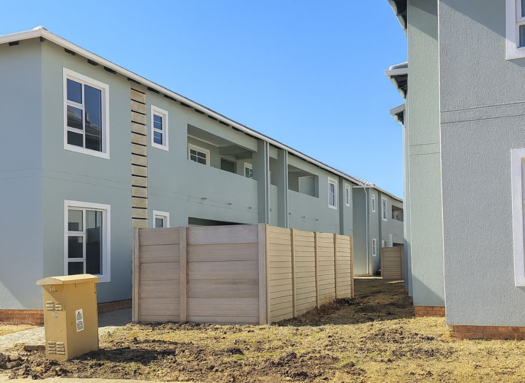 Exterior view of the apartment blocks at Greenwood Gardens in Germiston, showing modern double-storey units, balconies and boundary fencing.